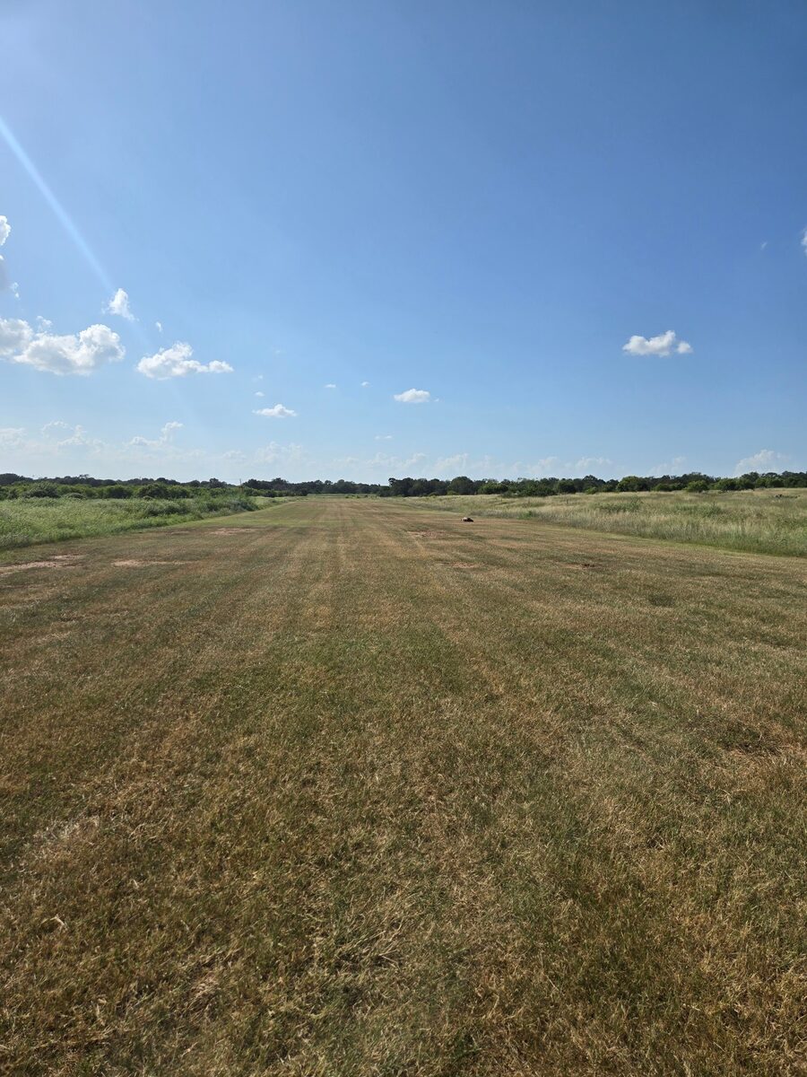 Mowed grass airstrip under a clear summer sky